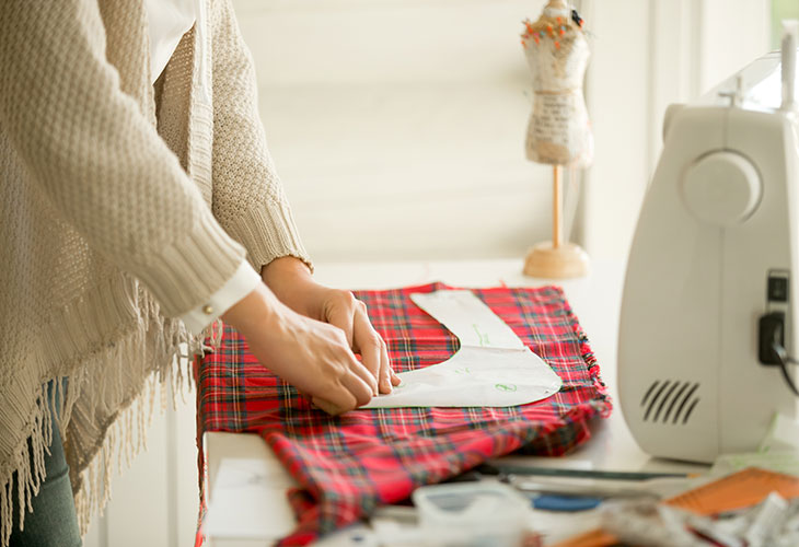 Woman working with sewing pattern in tartan fabric